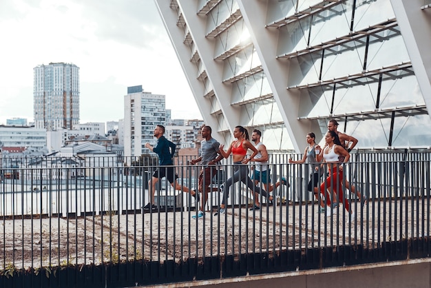 Tutta la lunghezza dei giovani in abbigliamento sportivo che fa jogging mentre si esercita sul ponte all'aperto