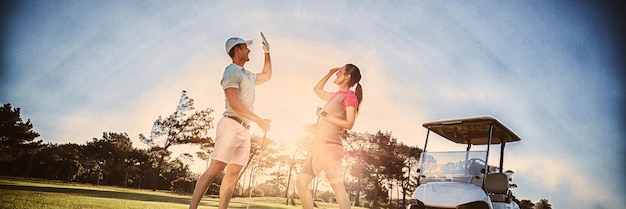 Tutta la lunghezza della coppia di giocatori di golf che dà il cinque