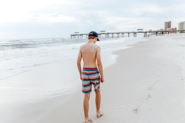 Tutta la lunghezza di un ragazzo adolescente che cammina sulla spiaggia