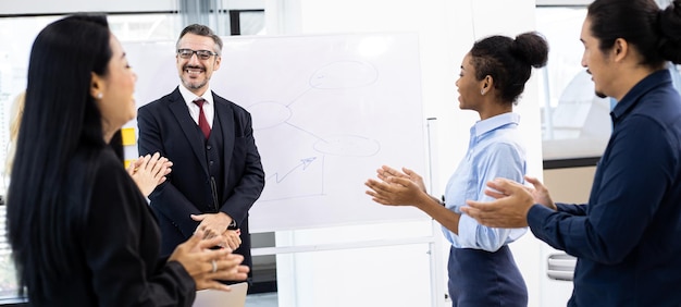 Tutti allo stand della riunione sorridono e applaudono il leader della squadra che ha lavorato con successo con felice. Concetto di affari di riunione di gruppo.