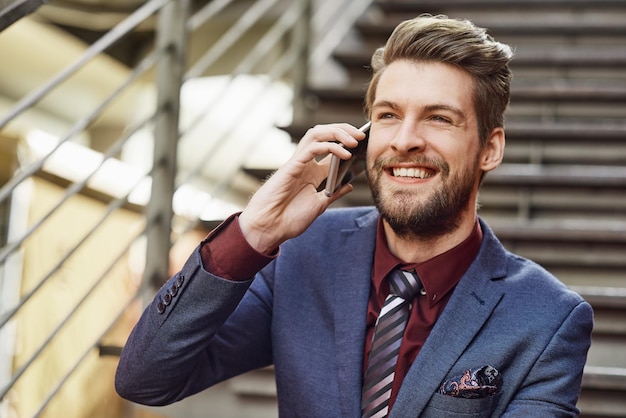 È tutto su stile e status Ritratto di un giovane uomo d'affari felice che usa il suo telefono mentre è fuori città