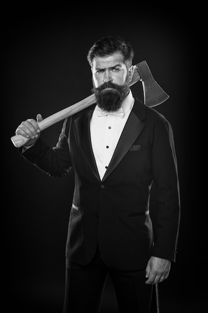 Tuxedo party boss brutale uomo hispter tenere ascia sfondo nero fiducioso uomo d'affari vestito formale serio maschio barbiere con ascia Barbershop smoking uomo con barba baffi toelettatura con lama affilata