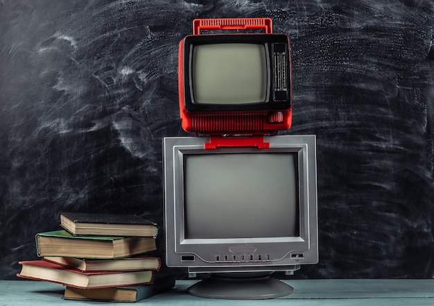 TV retrò e pila di libri su sfondo lavagna. Didattica a distanza televisiva.