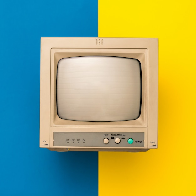 TV retrò su superficie gialla e blu. La vista dall'alto. Elettronica d'epoca.