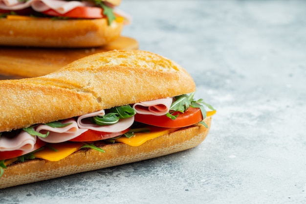 Two Long baguette Sandwiches with ham and cheese.