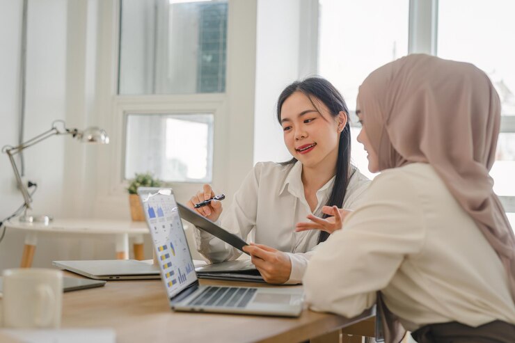 Photo two multi ethnic female office workers discussing financial market data and comparisons in the office