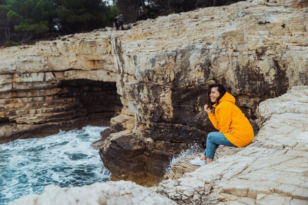 Ubicazione della donna sul bordo della scogliera che osserva le grandi onde del mare