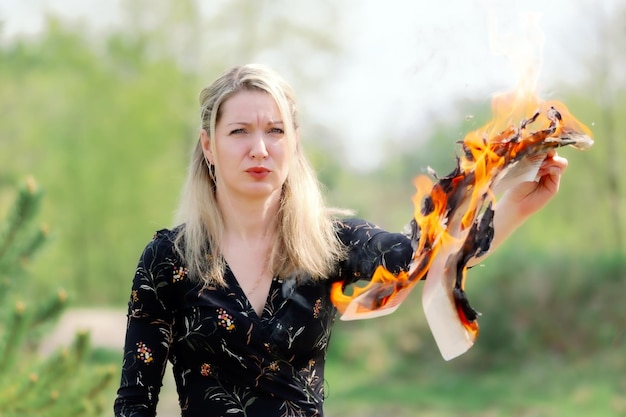 Ucraina Romny 25042023 Una donna protesta contro le notizie false dei media Ritratto di una giovane donna che guarda un giornale in fiamme Un giornale in fiamme nelle mani di una donna concetto di notizie calde e di ultima ora