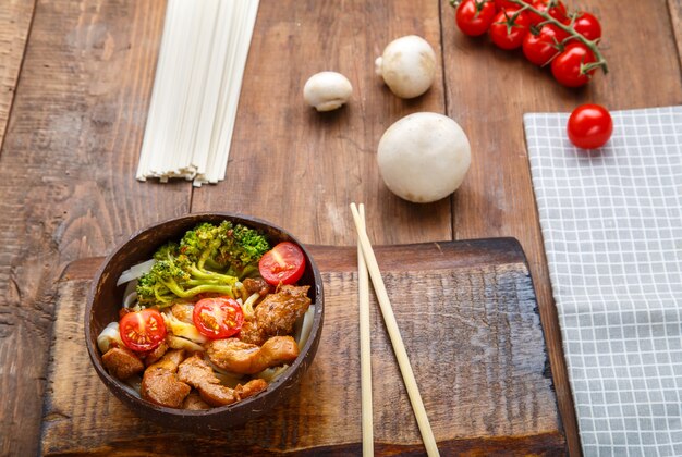 Udon con pollo in salsa giapponese su un piatto di gusci di cocco