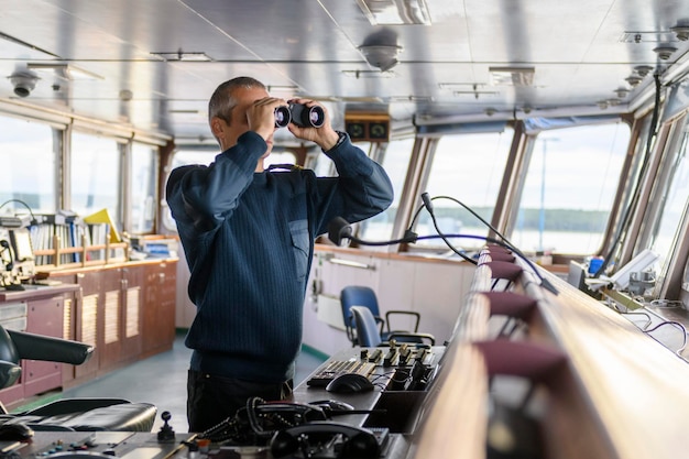 Ufficiale di coperta con binocolo sul ponte di navigazione Marinaio a bordo della nave Spedizione commerciale