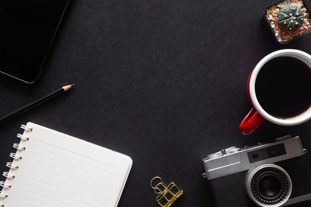 Ufficio scrivania nera con laptop, smartphone e altre forniture di lavoro con una tazza di caffè. Vista dall'alto con spazio di copia per inserire il testo. Area di lavoro di design su elementi essenziali del tavolo della scrivania su un piano disteso.