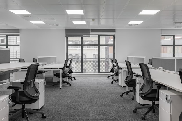Ufficio vuoto nei toni del grigio con tavoli e sedie e grandi finestre dal pavimento al soffitto in un centro riunioni