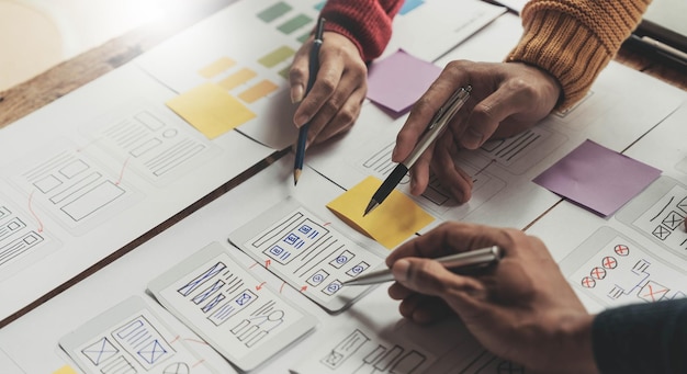 UI UX creative designer team designing wireframe layout for responsive mobile smartphone application in office