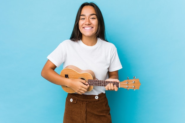 Ukeleele di gioco felici della giovane donna indiana isolate