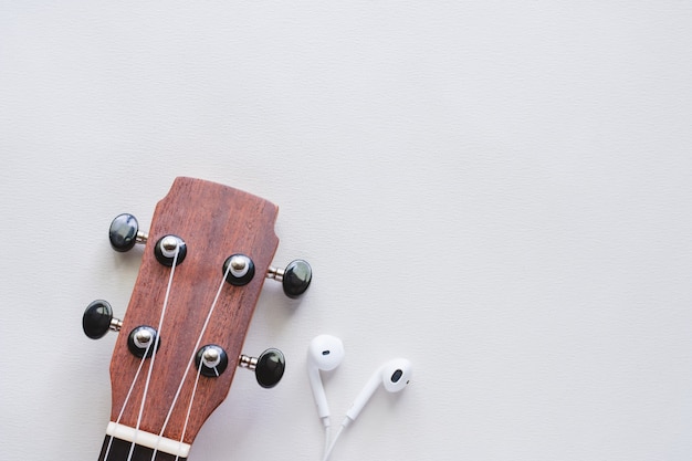 Ukulele con auricolari su sfondo bianco