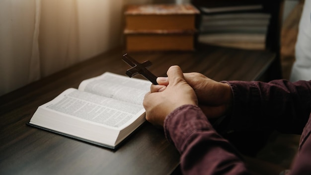 Umano seduto e studio delle scrittureLa croce di legno nelle mani Concetti di educazione cristiana Le Sacre Scritture