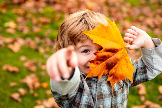 Umore autunnale Ragazzino in autunno foglie d'arancio all'aperto