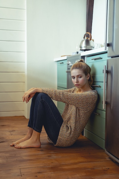 Umore depressivo. Ragazza bionda seduta sul pavimento e guardando verso il basso