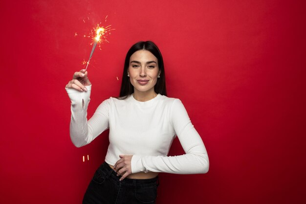 Umore di festa - giovane donna sorridente in un maglione bianco che tiene le stelle filanti