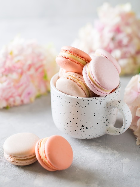 Umore primaverile ancora in vita con amaretti in tazza e fiori su bianco