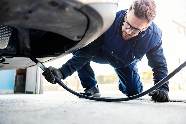 Un addetto al servizio auto che controlla i gas di scarico dell'auto durante il servizio tecnico