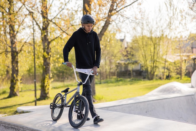 Un adolescente con uno sguardo triste sul viso torna a casa e scende da una rampa nel parco guidando la sua bici bmx