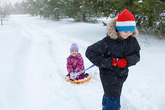 Un adolescente fa rotolare una bambina nella neve su una pista di pattinaggio di plastica