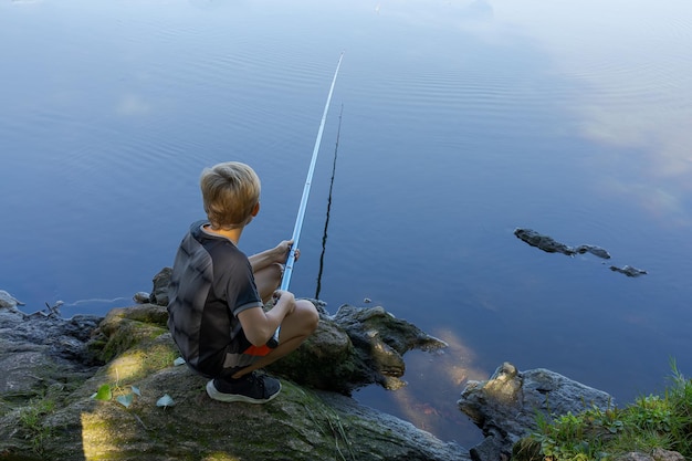 Un adolescente in viaggio di pesca in attesa di un boccone di pesce Pesca sportiva sul fiume in estate