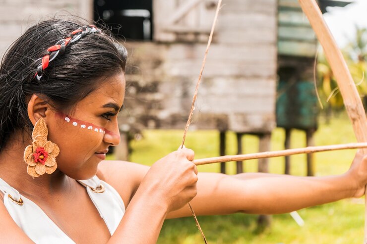 Un'adolescente indigena con una faccia dipinta e scagliando frecce con un arco di legno in una comunità dei Caraibi del nord in Nicaragua