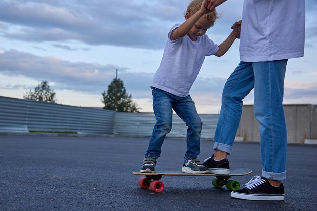 Un adolescente insegna a un ragazzo come andare sullo skateboard