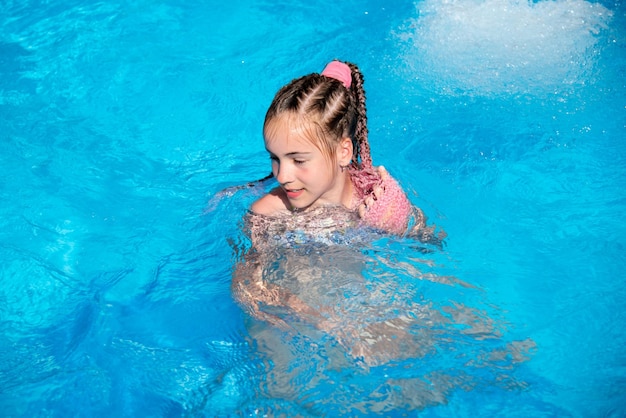 Un'adolescente si bagna in piscina. Estate. Vacanza.