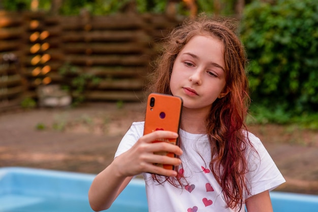 Un'adolescente si fa un selfie in piscina. Bambino e tecnologia.