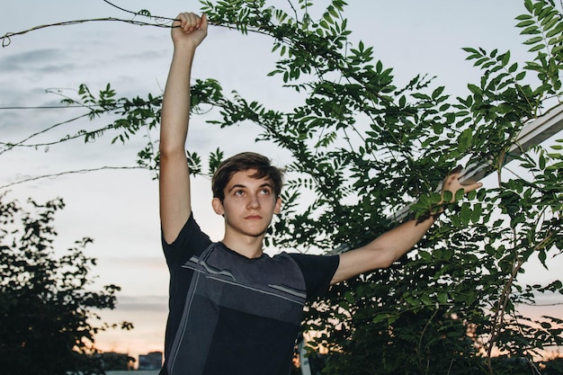 Un adolescente si prende cura di un giovane albero facendo giardinaggio per salvare il mondo concetto natura ambiente ed ecologia Educazione e scolari piantano giovani alberi da frutto all'aperto