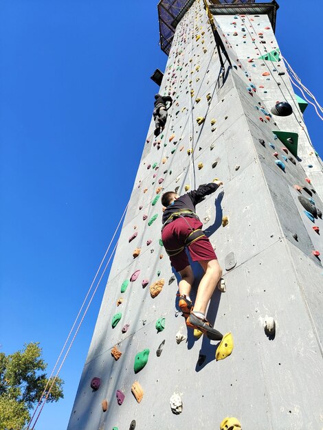 Un adolescente si sta allenando e si sta arrampicando su una parete di arrampicata su una torre speciale