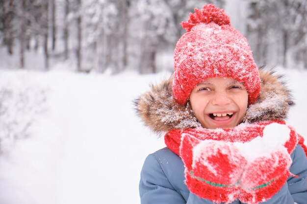 Un'adolescente soffia sulla neve tra i palmi delle mani e sventola guanti e un cappello lavorato a maglia che cambia il tempo