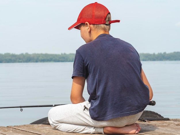 Un adolescente sta pescando con una canna Il concetto di vacanza ricreativa