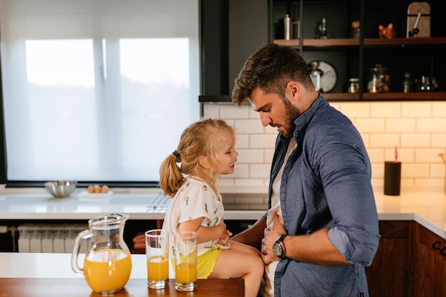 Un'adorabile bambina e suo padre che bevono succo insieme a casa