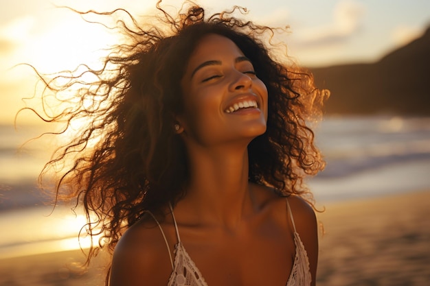 Un'adorabile donna di origine mista che sorride mentre si rilassa su una spiaggia al tramonto con gli occhi chiusi e i capelli che soffiano al vento