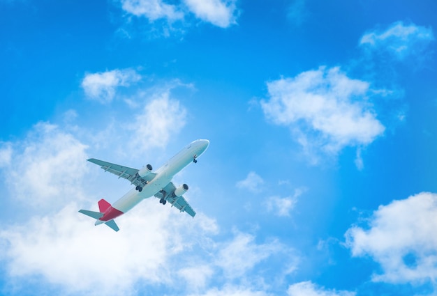 Un aereo che vola nel cielo azzurro con nuvole bianche