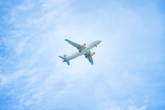 Un aereo che vola nel cielo azzurro con nuvole bianche