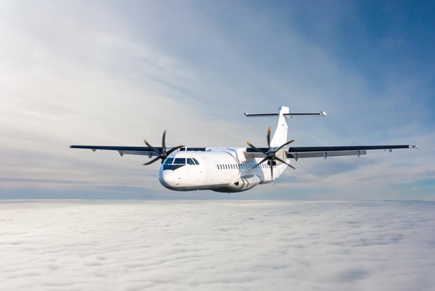 Un aereo turboprop passeggeri bianco vola nell'aria sopra le nuvole