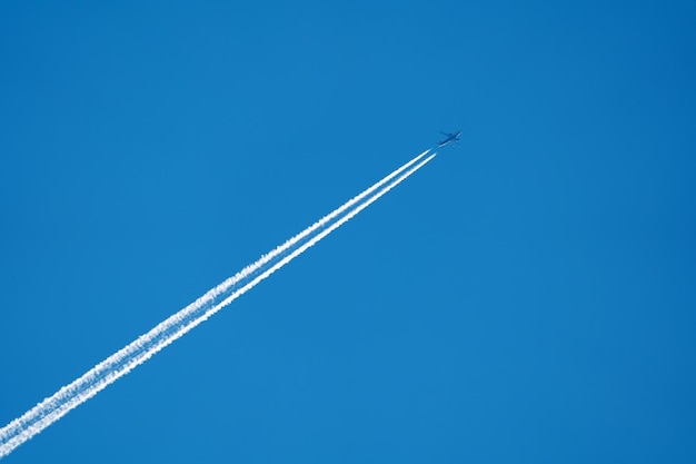 un aereo volante con una scia di fumo bianco su uno sfondo di cielo blu