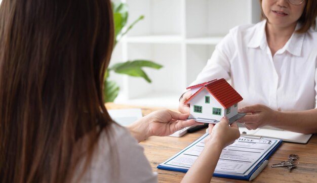 Un agente immobiliare o un agente assicurativo lavora con modelli di casa e contratti di vendita di immobili per la casa all'interno dell'ufficio Approvazione del prestito ipotecario e concetto di assicurazione