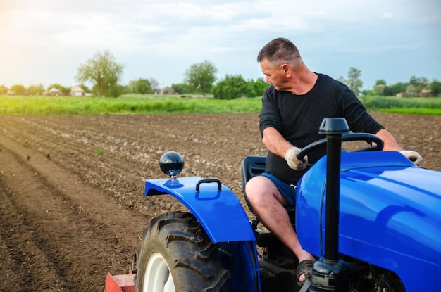 Un agricoltore su un trattore lavora nel campo Liberare il terreno macinato dalle vecchie colture Coltivazione del terreno Ammorbidimento del suolo e distruzione dell'apparato radicale del raccolto precedente Agricoltura