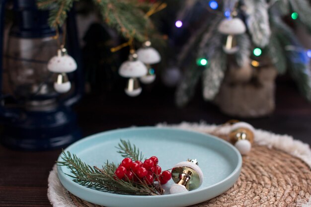 Un albero di Natale con giocattoli e un piatto con bacche di viburnum rosso e fette d'arancia luci di Capodanno