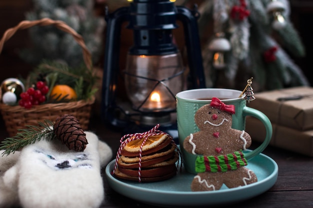 Un albero di Natale con giocattoli e una tazza calda di tè d'arancia caldi guanti bianchi e un uomo di pan di zenzero