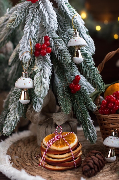 un albero di Natale con luci un cesto di vimini con mandarini e fette di arancia secca coni e giocattoli di albero di Natale