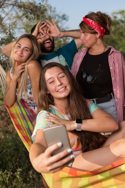 Un'allegra compagnia di giovani, quattro persone, su un'amaca, creano un selfie per la memoria, le vacanze estive