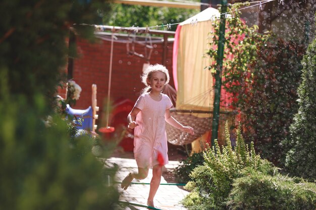 Un'allegra e affascinante bambina di sette anni si gode una soleggiata mattina d'estate e si diverte nel giardino di casa.