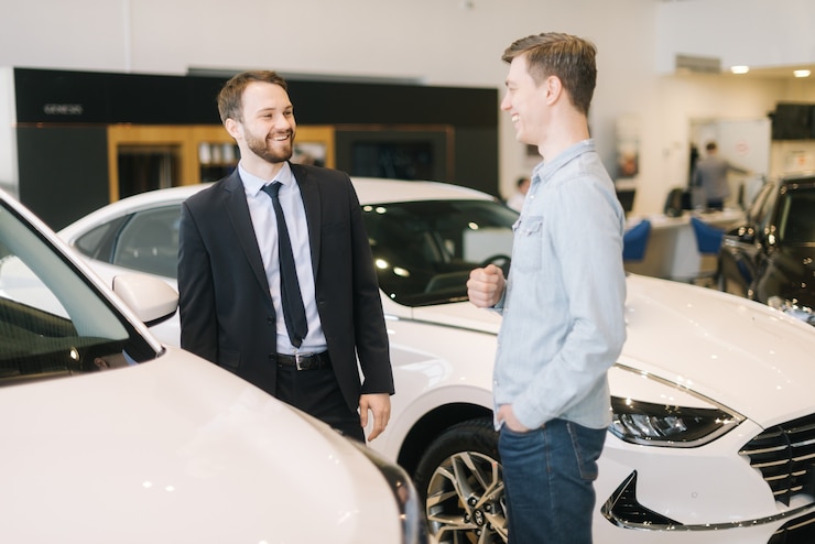 Foto un allegro venditore di automobili che indossa un tailleur sta conversando con un bel giovane ricco